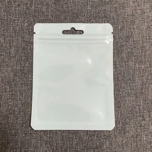 Close-up of a white resealable zipper bag for jewelry packaging on a grey fabric background