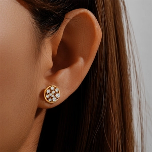 Close-up of gold round cluster stud earrings with clear zircon stones on ear