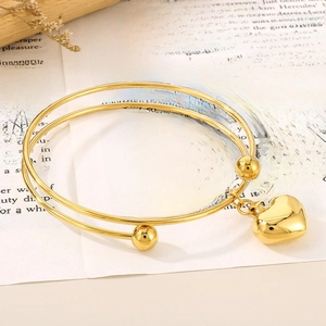 Detailed view of 18K gold plated heart charm bracelet on a vintage letter background