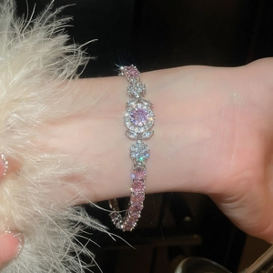 Macro detail of silver flower bracelet with pink zircon stones and white feathers