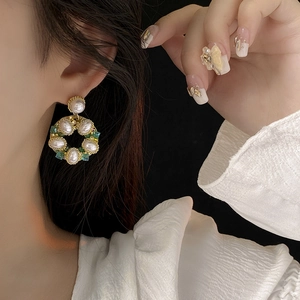 Primo piano di orecchini a cerchio con perle e cristalli colorati indossati da una modella