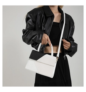 Sac bandoulière tendance bicolore noir et blanc présenté sur un mannequin