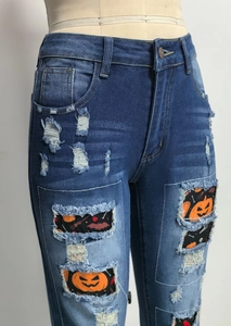 Detail der blauen Jeans mit Halloween Kürbis und Fledermaus Mustern in den Rissen