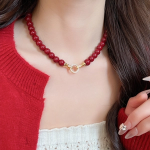 Detail of red acrylic beads and golden zircon pendant on a necklace worn by model