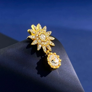Macro view of gold sunburst drop earrings with sparkling crystals on a blue texture