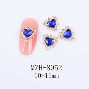 Detailed view of hollow heart nail jewels with blue stones and gold crown settings