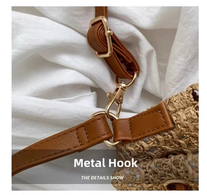 Detail of durable golden hardware hook and brown leather strap on straw bucket bag