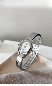 Detail of silver bangle watch with white dial on textured fabric and ceramic tray