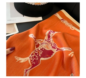 Close-up of thick orange horse pattern shawl with soft knitted texture and vibrant finish