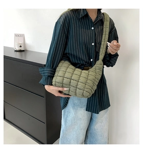 Close-up of sage green quilted puffer bag featuring a soft padded texture and wide strap