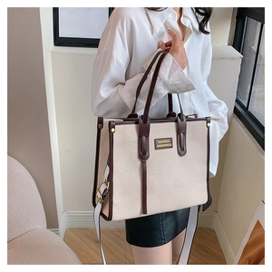 Detail of canvas tote bag with brown leather handles and adjustable shoulder strap