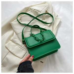 Detail of green PU leather crossbody bag with chain accent on a white blazer