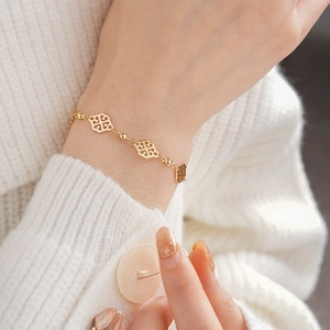 Detail of a vintage gold hollow diamond-pattern bracelet on a white sweater sleeve