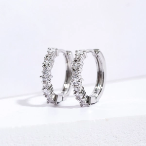 Close-up of silver hoop earrings featuring square blue zircon and clear stones