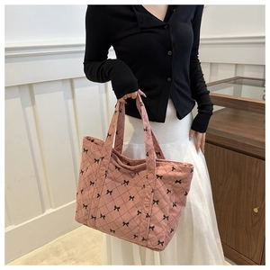 Pink corduroy tote bag with black bow pattern and diamond quilting shown with model