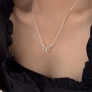 Close-up of minimalist silver double loop necklace worn on a model against a black background