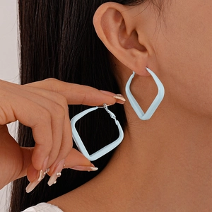 Close-up of matte light blue geometric square hoop earrings worn by a female model