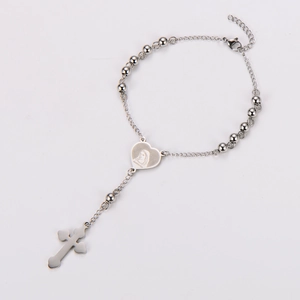 Macro detail of silver rosary bracelet with heart-shaped medal and cross pendant