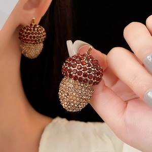 Close-up of vintage acorn earrings with red and champagne crystals on gold metal