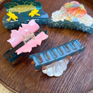 Detailed close-up of acetate starfish and shell hair claws with pearls on a wooden tray