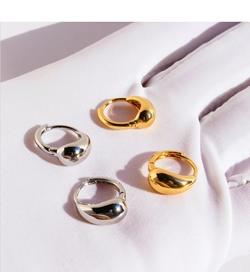 Gros plan de boucles d'oreilles gouttes minimalistes dorées et argentées sur fond