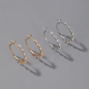 Close-up of gold and silver hoop earrings with marquise-cut sparkling zircon stones