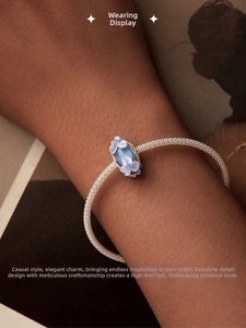 Close-up of sky blue glass charm with white flowers on silver mesh bracelet for women