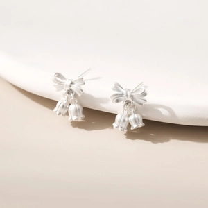 Macro shot of matte silver butterfly lily of the valley earrings on a white display stand