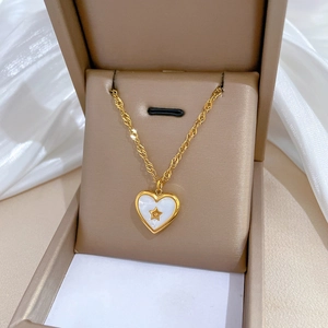 Detail of heart shell pendant with star motif in gold finish on beige jewelry box