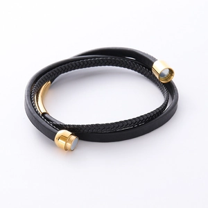 Detail of multi-layer black braided leather bracelet with golden magnetic clasp