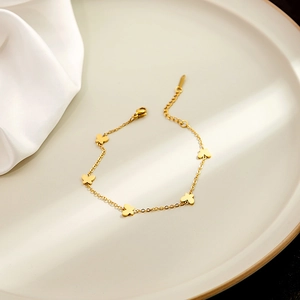 Close-up of golden butterfly charm bracelet featuring five delicate metal pendants and lobster clasp