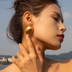 18k gold plated stainless steel matte oval stud earrings worn by a model in nature