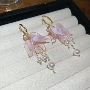 Detail of pink petal tassel earrings with white pearls on a beige velvet jewelry tray