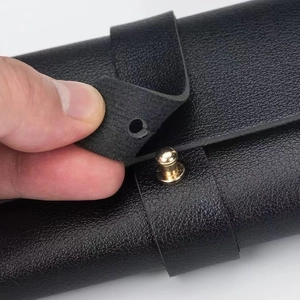 Detail of black lychee grain leather glasses case with gold metal stud closure