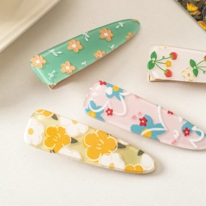 Flat lay detail of four cute acrylic floral hair clips in various colorful patterns