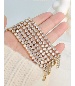 Close-up of stacked gold tennis bracelets with sparkling round-cut crystals on the wrist