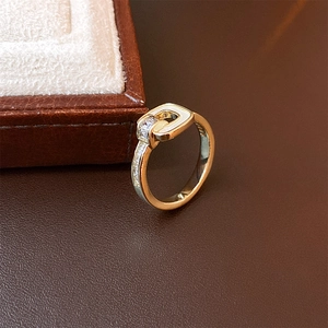 Detailed close-up of golden buckle ring with sparkling zircons on dark leather surface