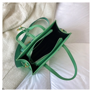 Interior view of bright green textured leather tote bag with wide strap and zip pocket