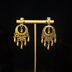 Detailed view of golden bohemian long drop tassel earrings on a display stand