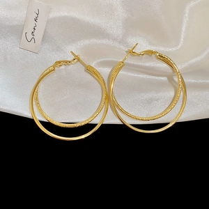 Detailed view of 18k gold plated double hoop earrings featuring a textured crossover design