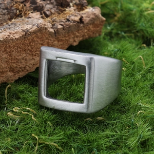 Détail d'une bague géométrique avec finition en argent brossé sur mousse et écorce
