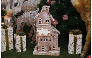 Close-up of wooden Christmas house ornament with snow effect and festive holiday decor