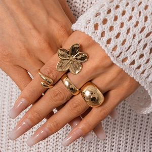 Detailed close-up of a 4-piece gold metal ring set featuring a floral and geometric design