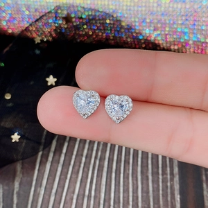 Detailed view of heart-shaped zircon stud earrings held to show delicate scale and shine