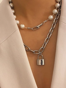 Detail of layered pearl necklace and silver chain with rectangular padlock pendant