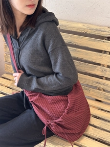 Detail of red gingham shoulder bag featuring side bow ties and soft nylon texture