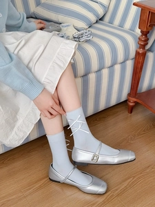 Détail de chaussettes en coton bleu clair avec nœuds en ruban blanc et chaussures argentées