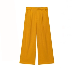 Détail d'un pantalon large orange à taille haute en tissu fluide avec bouton à la ceinture
