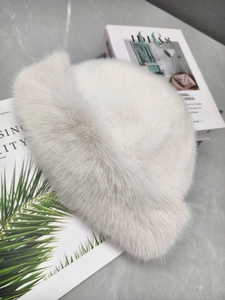 Detail of plush faux fur winter bucket hat in cream white on a marble background