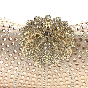 Detailed macro view of the golden floral clasp and sparkling rhinestones on the evening bag